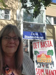 Lena M Johansson med debutromanen Det bästa som hänt, utanför entrén till stadsbiblioteket i Norrtälje. 
